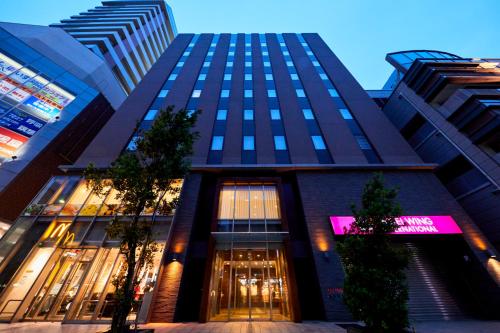 a tall building with a lit up sign on it at Hotel Wing International Kobe - Shinnagata Ekimae in Kobe