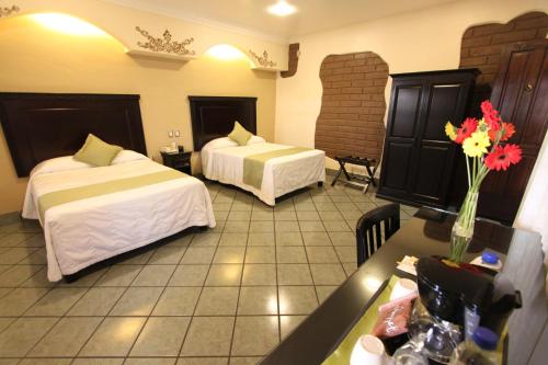 a hotel room with two beds and a table with flowers at Hotel CasAntica in Oaxaca City
