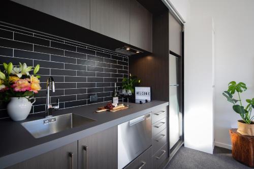 a kitchen with a sink and a black tile wall at The Arrow Nest in Arrowtown