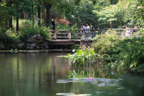 people walking across a bridge over a pond in a park at Zhejiang Xizi Hotel in Hangzhou