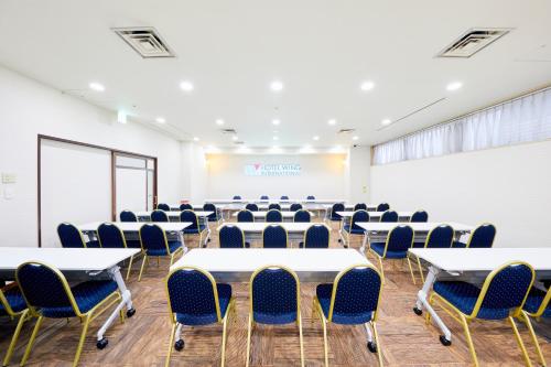 a room with tables and chairs and a projection screen at Hotel Wing International Kobe - Shinnagata Ekimae in Kobe