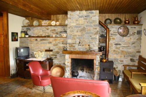 a living room with a stone fireplace and a red chair at Ninho do Melro - Turismo Rural Bragança in Bragança