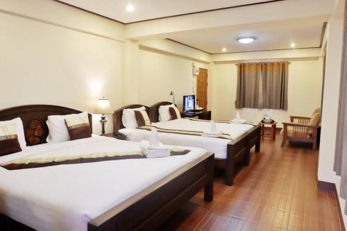 a hotel room with two beds and a television at NanBaanKhun Hotel in Nan