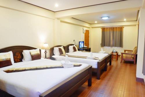 a hotel room with three beds in a room at NanBaanKhun Hotel in Nan