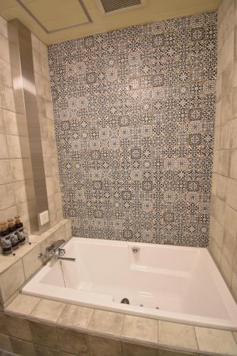 y baño con bañera blanca y pared de azulejos. en Hotel Pinon - Adult Only en Kai