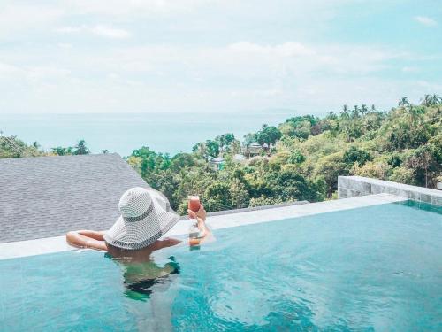 a person sitting in a swimming pool with a drink at Mayara pool villas - Adults only in Haad Yao