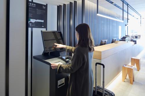 a woman standing at a cash register in an office at hotel androoms Nagoya Fushimi in Nagoya