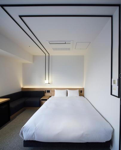 a bedroom with a large white bed with a ceiling at hotel androoms Nagoya Fushimi in Nagoya