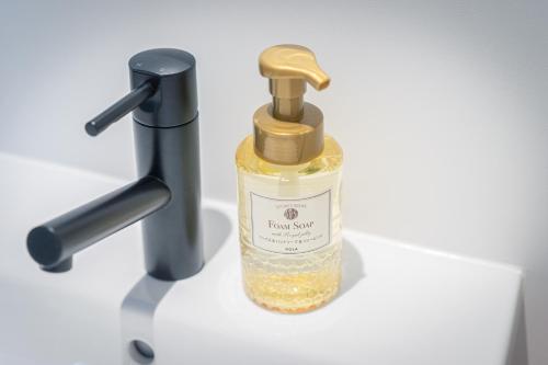 a bottle of liquid soap sitting next to a faucet at hotel androoms Nagoya Fushimi in Nagoya