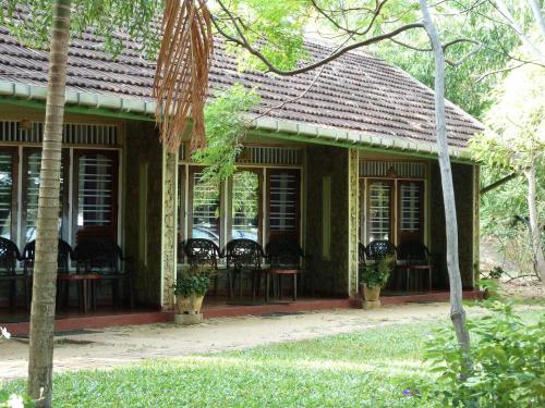 a green house with chairs and tables and windows at Riviera Resort in Batticaloa