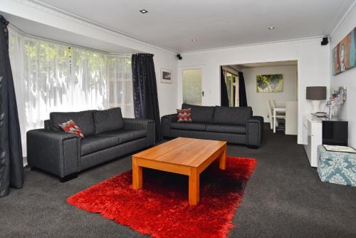 a living room with two couches and a coffee table at Relaxed 3BR Hideaway - Outdoor Living & Pets - Christchurch Holiday Homes in Christchurch
