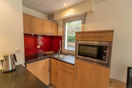 a kitchen with a microwave and a window in it at Les pieds dans l eau accès à la plage depuis la résidence in Trébeurden