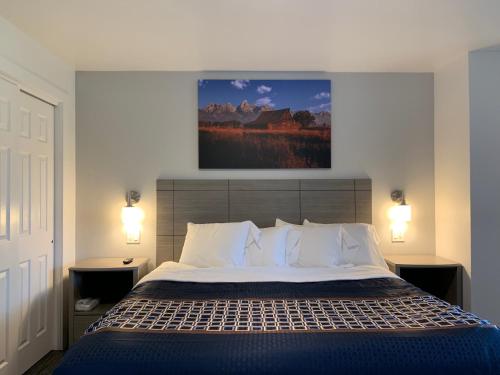 a bedroom with a bed and a painting on the wall at The Gunnison Inn at Dos Rios Golf Course in Gunnison
