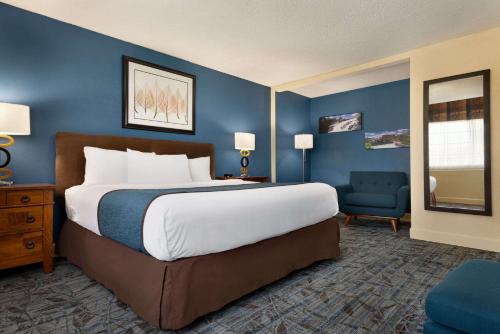 a bedroom with a large bed and a blue wall at Ramada by Wyndham Spokane Airport in Spokane