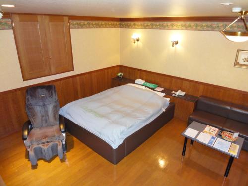 a bedroom with a bed and a chair and a table at Annex Tamayu 大人専用 in Matsue