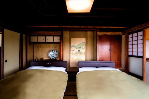 two twin beds in a room with two windows at そわか楼 in Fukuyama