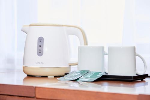 a coffee maker and two cups on a counter at Hotel Wing International Kobe - Shinnagata Ekimae in Kobe