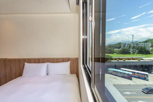 a bedroom with a bed and a window with a view at Traveller Inn Tiehua Cultural and Creative Hotel II in Taitung City