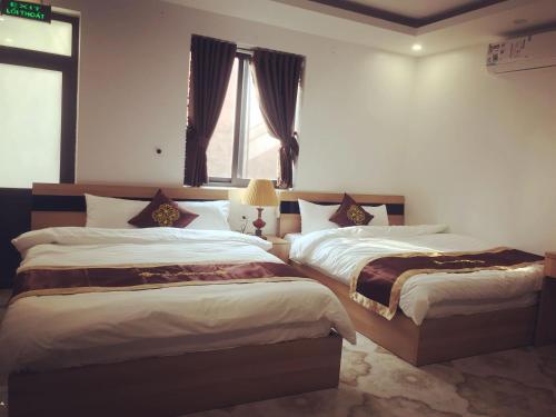 a bedroom with two beds and a window at Ngoc Huyen Hotel in Tam Ðảo