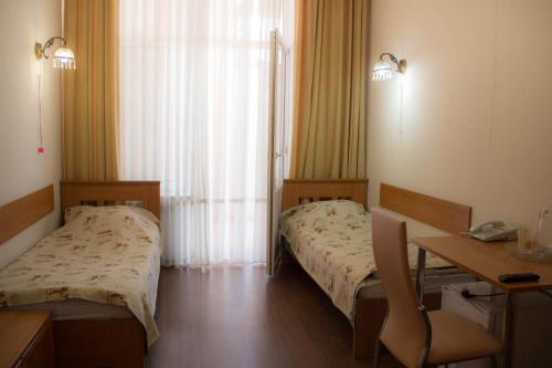 a hospital room with two beds and a desk and a table at Pyatigorskaya Klinika Sanatorium in Pyatigorsk