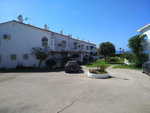 a large white building with a car parked in a parking lot at BUNGALOW CHARO in Torre de Benagalbón