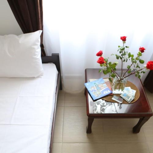 a bed and a table with a vase with flowers on it at Apartments & Dream Rooms in Niš