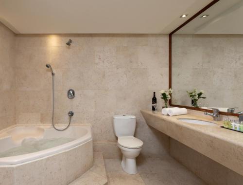 a bathroom with a tub and a toilet and a sink at King Solomon Hotel Tiberias in Tiberias