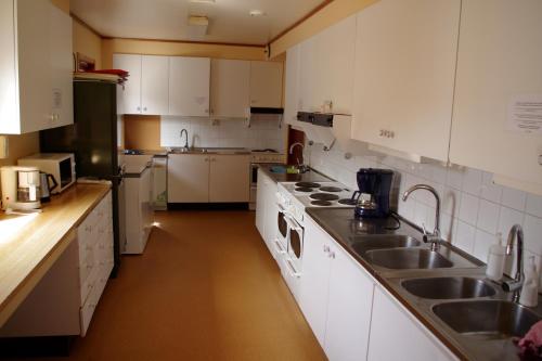 a kitchen with white cabinets and a sink at Halens Camping och Stugby in Olofström