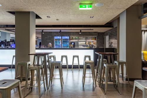 a row of stools in a restaurant with a bar at a&o Wien Hauptbahnhof in Vienna