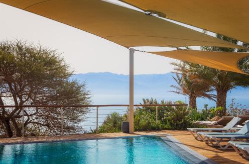 a swimming pool with chairs and an umbrella at Ein Gedi Kibbutz Hotel in Ein Gedi