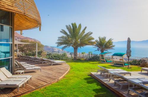 a house with a deck with lounge chairs and the ocean at Ein Gedi Kibbutz Hotel in Ein Gedi