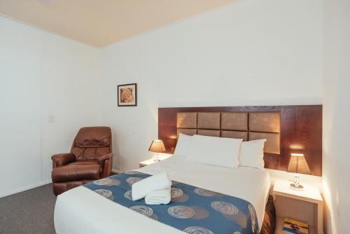 a hotel room with a bed and a chair at Coffs Windmill Motel in Coffs Harbour