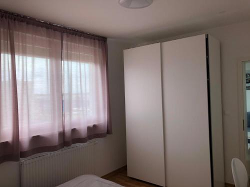 - une chambre avec une armoire blanche et une fenêtre dans l'établissement Apartman STAR, à Zagreb