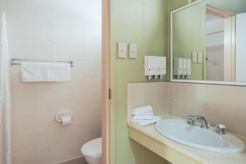 a bathroom with a sink and a toilet and a mirror at Coffs Windmill Motel in Coffs Harbour
