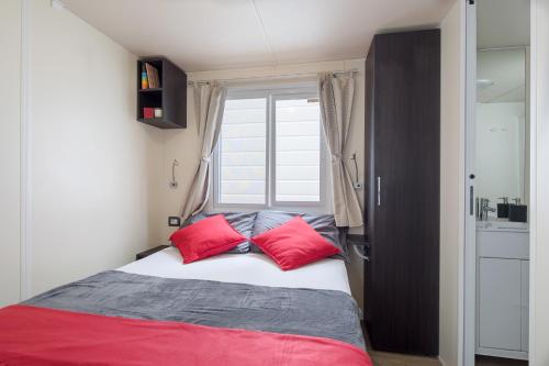 a bedroom with a bed with two red pillows at Camping Village Cavallino in Cavallino-Treporti
