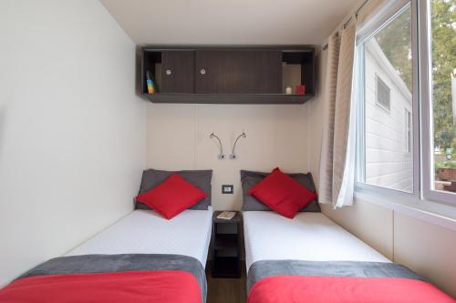 two beds in a small room with a window at Camping Village Cavallino in Cavallino-Treporti