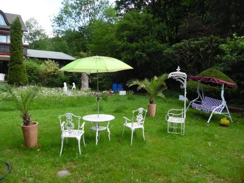 a table and chairs with an umbrella in a yard at Wellness und Romantik Hotel Helmboldt in Bad Sachsa