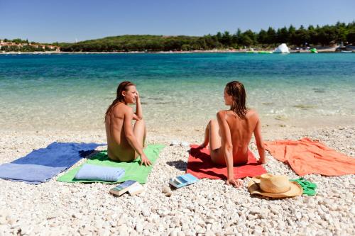 Due persone sono sedute sulla spiaggia di Koversada Villas Naturist Park a Vrsar
