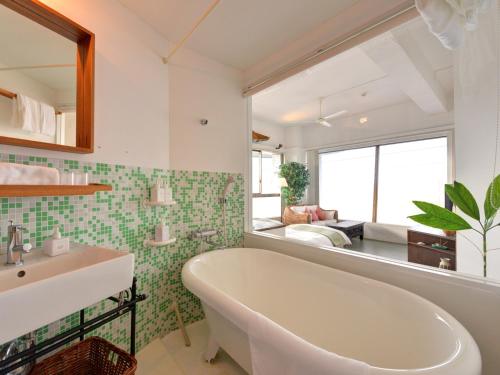 a bathroom with a tub and a sink and a mirror at Sound Swell Resort in Minamiboso