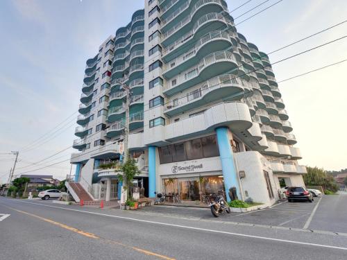 a large apartment building with a motorcycle parked in front of it at Sound Swell Resort in Minamiboso