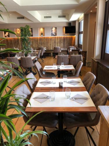 a restaurant with wooden tables and chairs and plants at Hôtel The Originals City Le Berry - proche centre-ville - Gare in Bourges