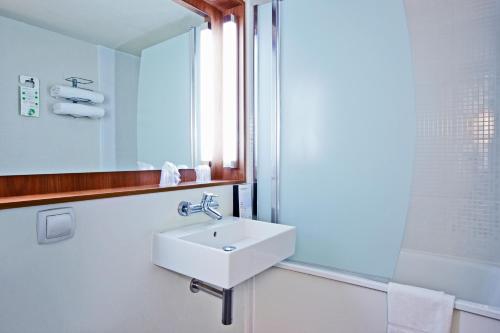 La salle de bains est pourvue d'un lavabo blanc et d'un miroir. dans l'établissement Campanile Chanas, à Chanas