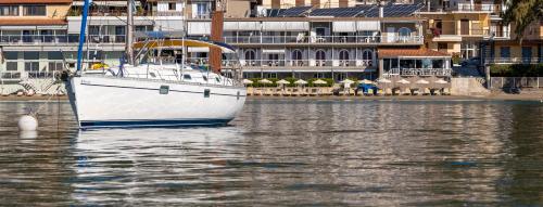 a white boat in the water next to buildings at Nelly's Apartments in Tolo