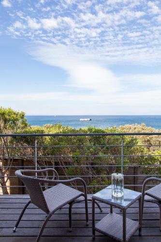a patio with chairs and a table and the ocean at Tintswalo Boulders in Simonʼs Town