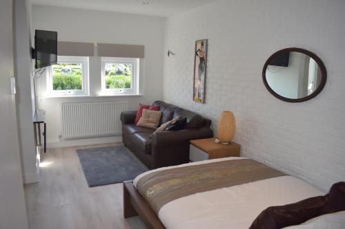 a bedroom with a bed and a couch and a mirror at Boatyard View in Sandwich