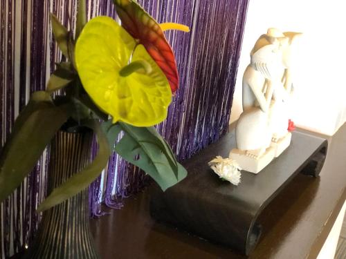 a vase with a flower and a statue on a table at Restay Nagasaki Aine (Adult Only) in Nagasaki