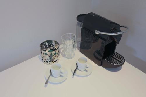 a table with a coffee maker and cups and glasses at EMPIRIC Keizersgracht in Amsterdam