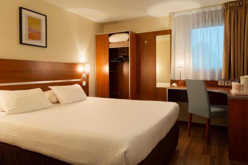 a hotel room with a bed and a desk and a desk at Comfort Hotel Aeroport Lyon St Exupery in Saint-Exupéry