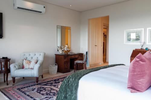 a bedroom with a bed and a chair and a desk at Tintswalo Boulders in Simonʼs Town