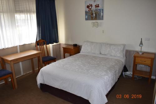 1 dormitorio con 1 cama, 1 mesa y 1 silla en Kaniva Midway Motel en Kaniva